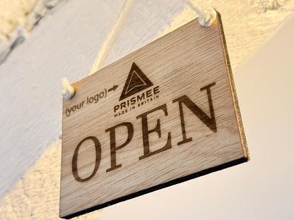 Wooden 'OPEN' sign with Prisme brand logo on a textured wall background