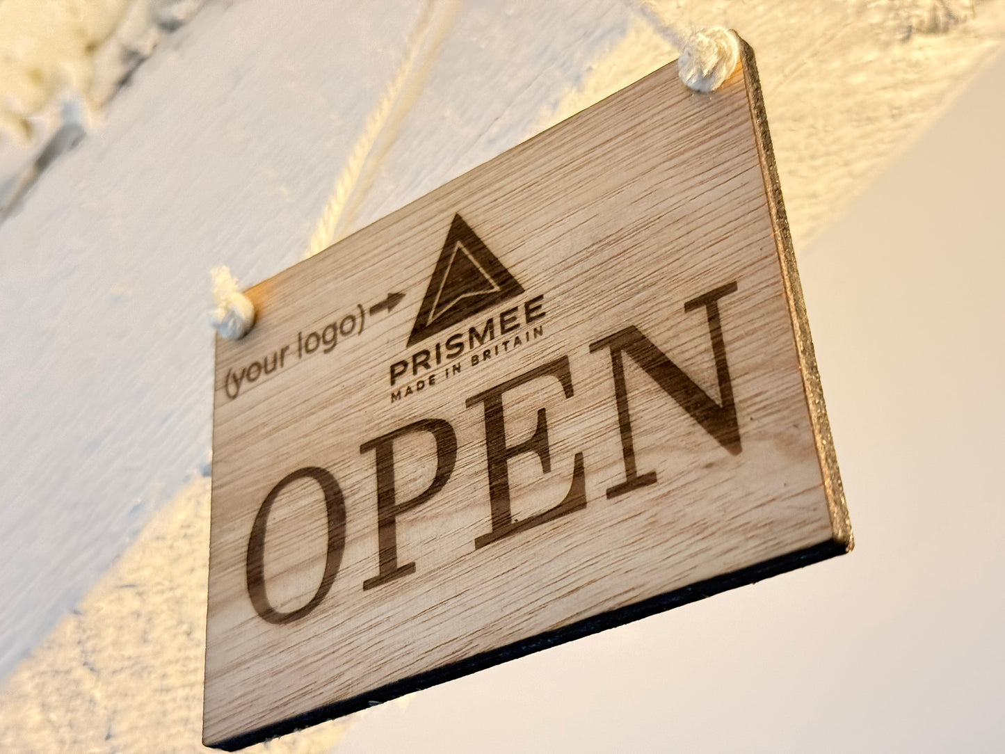 Wooden 'Open' sign with Prisme branding on a textured wall background