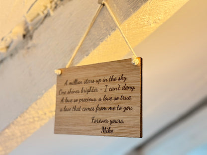 Wooden plaque with engraved text hanging against a blurred background