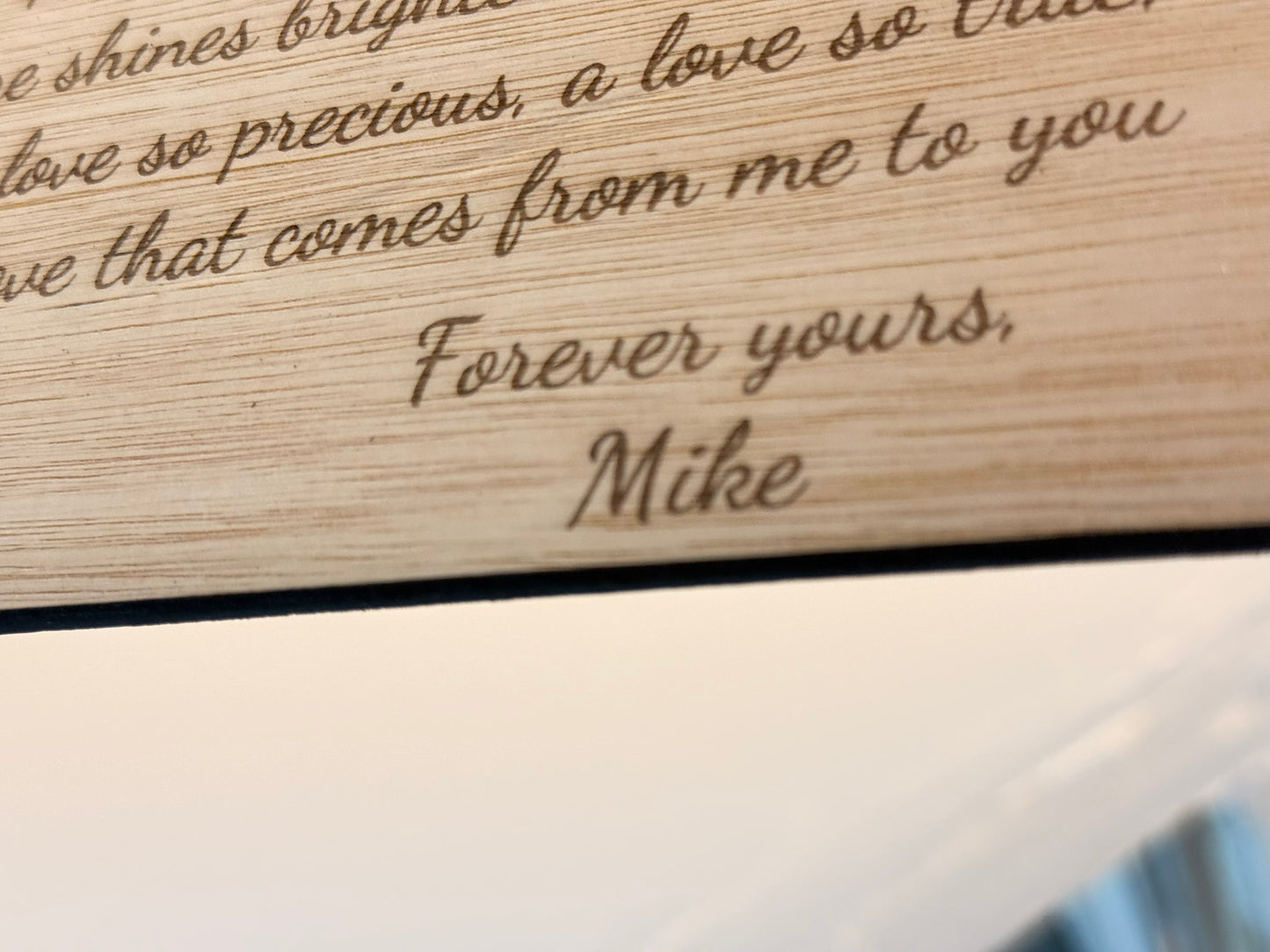 Wooden plaque with engraved message 'Forever yours, Mike' on a wooden surface.