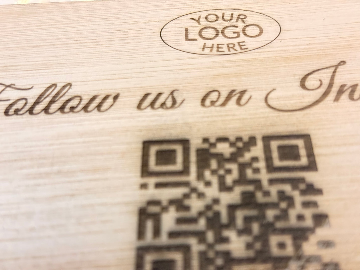 Wooden surface with engraved text and QR code, placeholder for 'Your Logo Here'.
