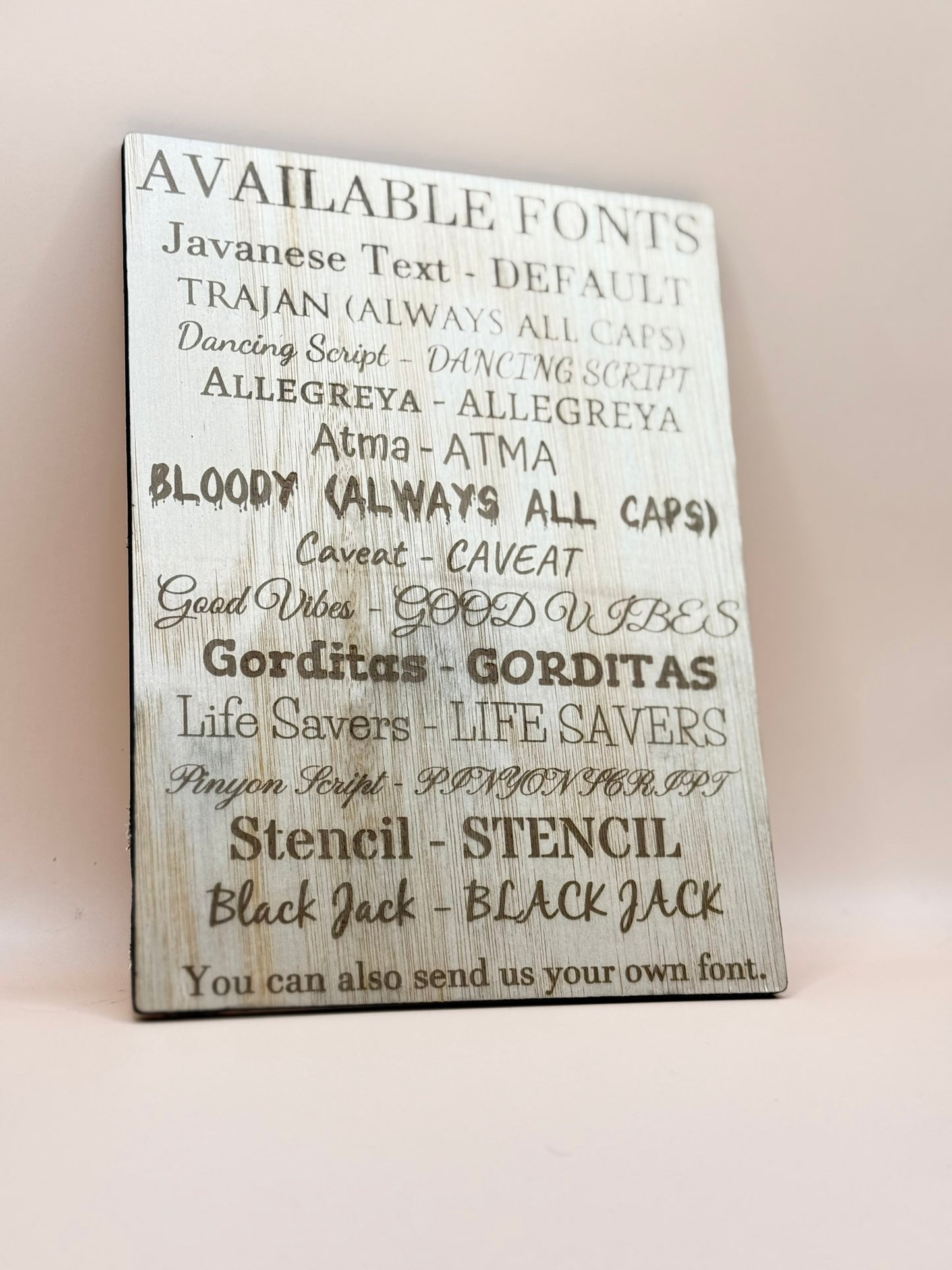Wooden sign with list of available fonts on a white background