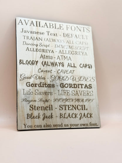 Wooden sign with list of available fonts on a white background